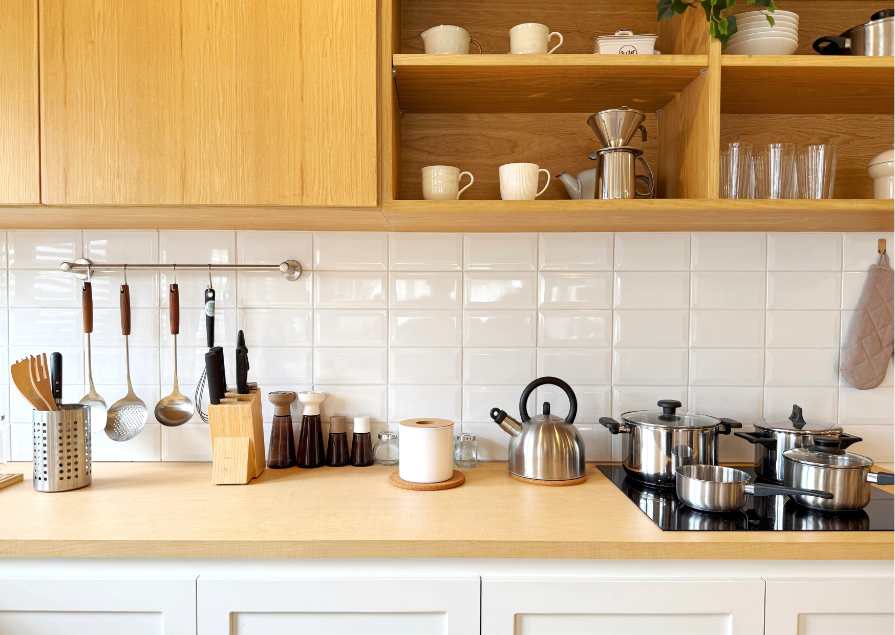 Intérieur de cuisine au style scandinave utilisant des panneaux de bois pour les meubles et les étagères hautes.