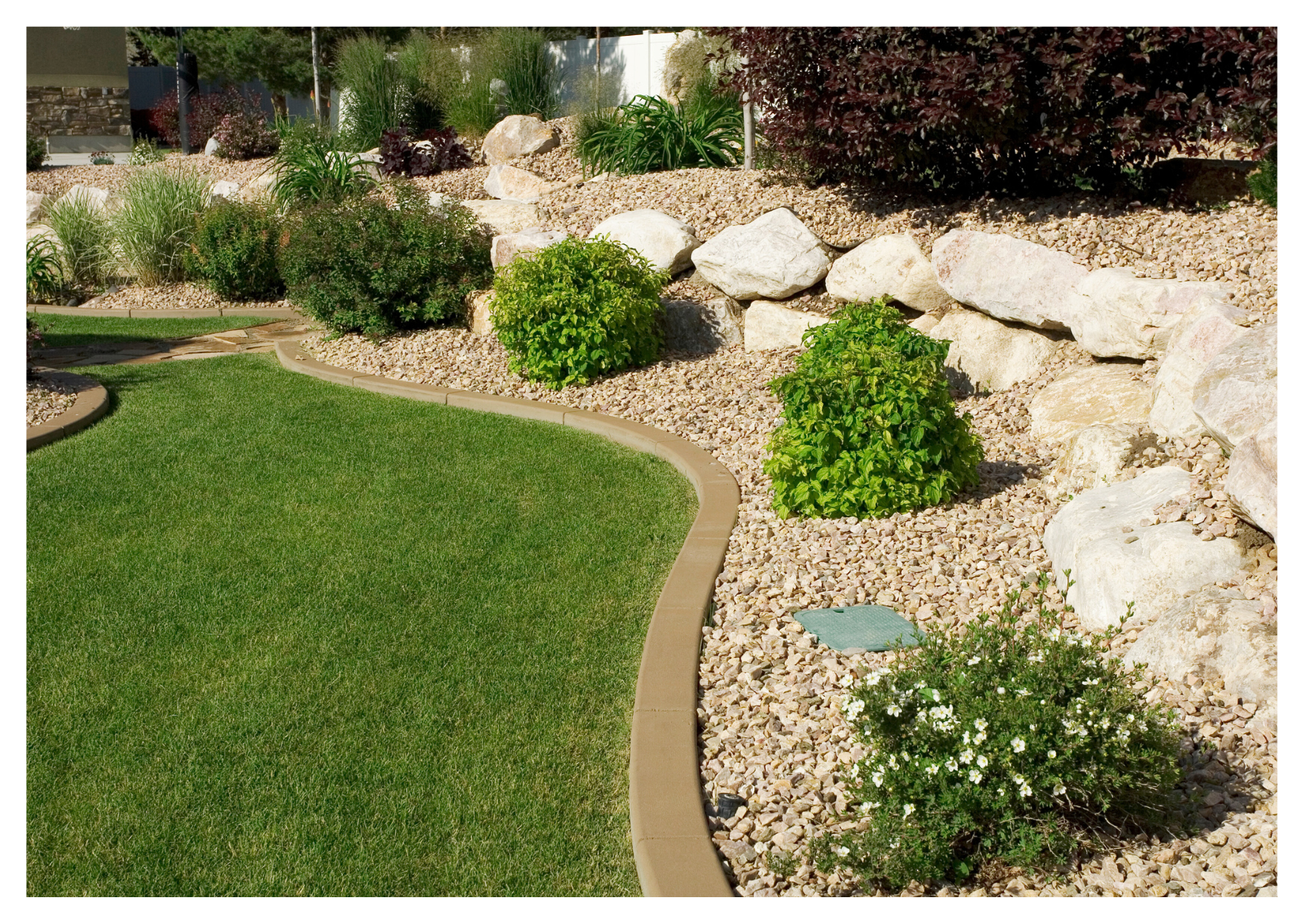 Bordure de jardin souple installée pour délimiter proprement une pelouse d'un massif de fleurs avec paillage minéral.