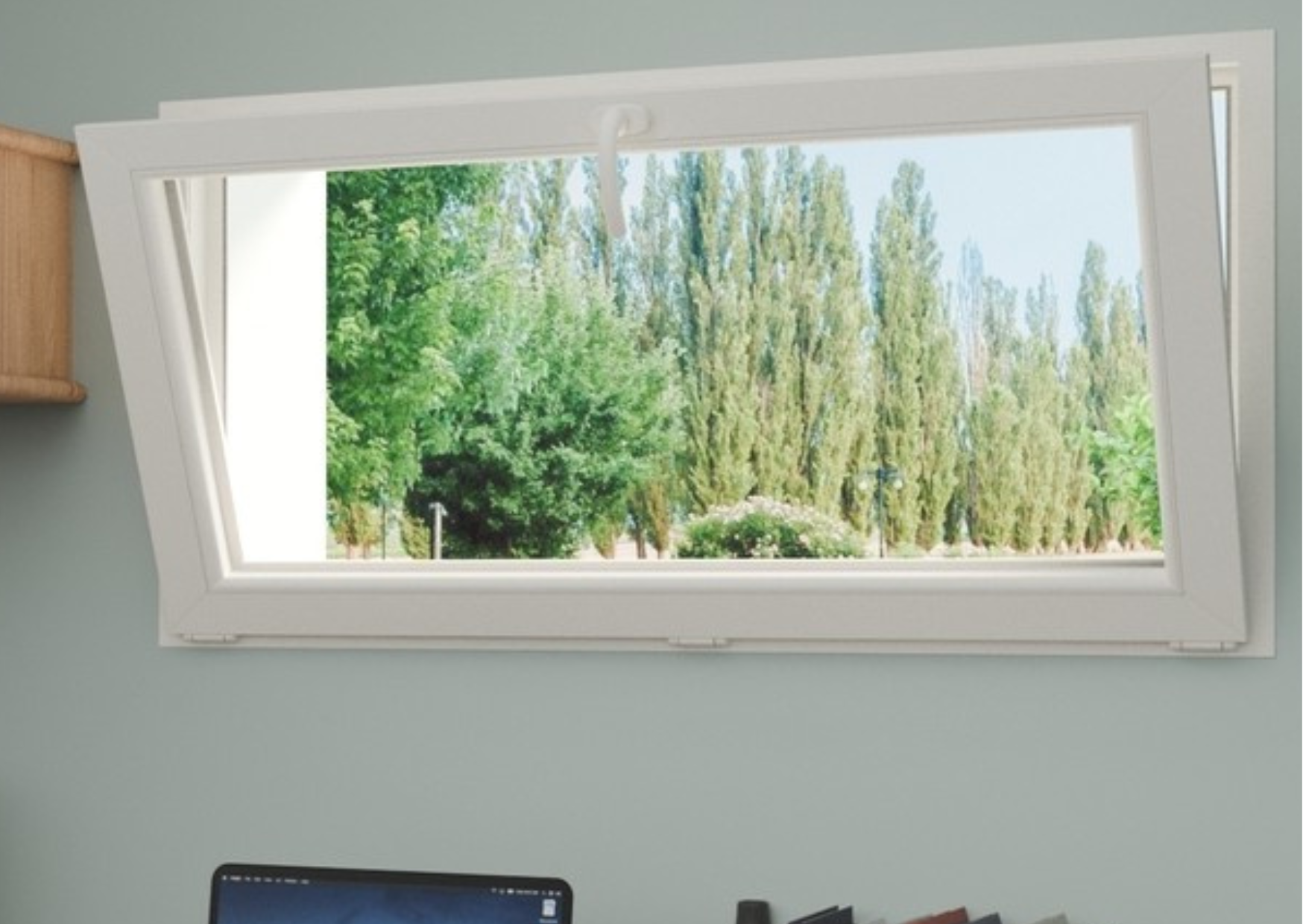 Châssis abattant en PVC blanc en position ouverte permettant l'aération d'une pièce avec vue sur l'extérieur.