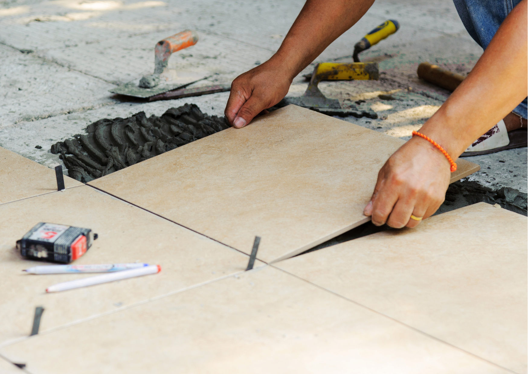 Artisan carreleur ajustant un carreau de grès cérame sur un lit de mortier colle pour une terrasse