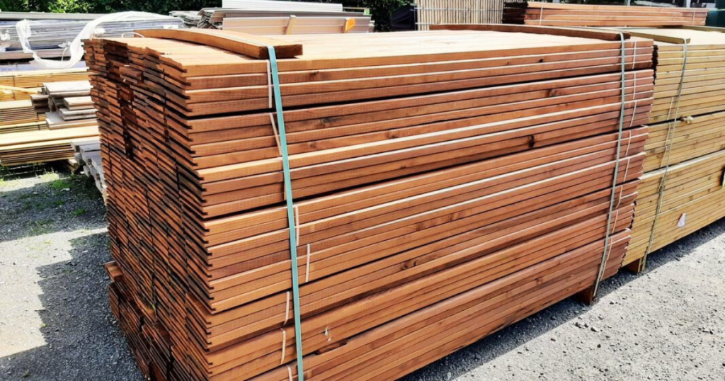 Palettes de lames de terrasse en bois stockées sur le parc de matériaux du Marais Fleuri.