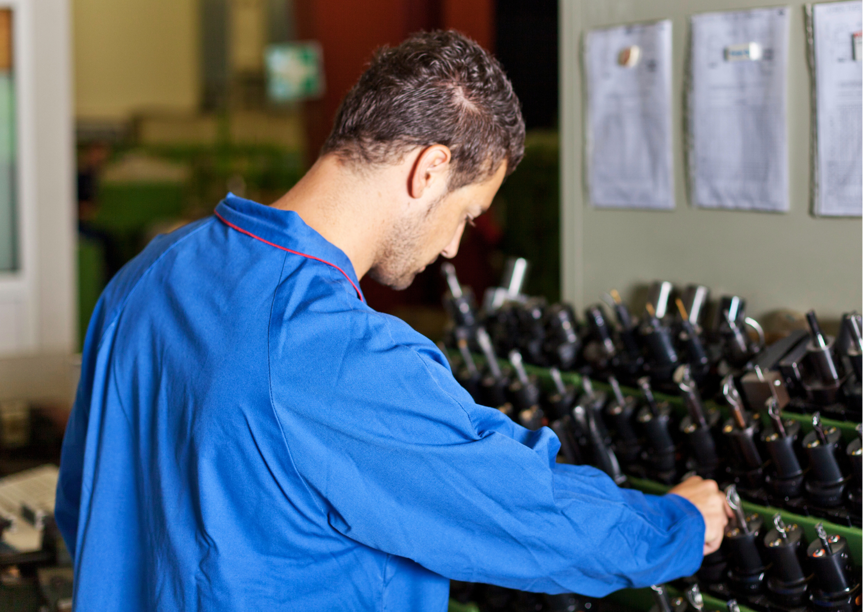 Homme portant une blouse de travail bleue résistante dans un environnement de production industrielle.