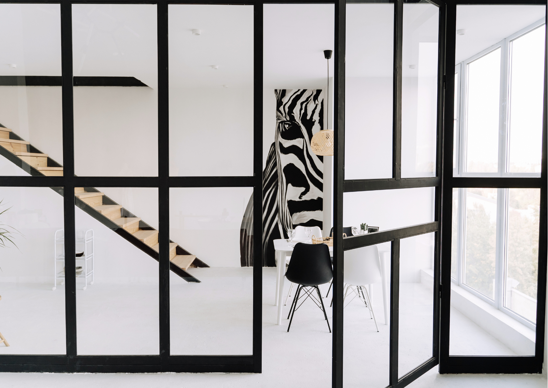 Verrière intérieure fixe à cadre noir avec grands carreaux installée dans une pièce de vie lumineuse.