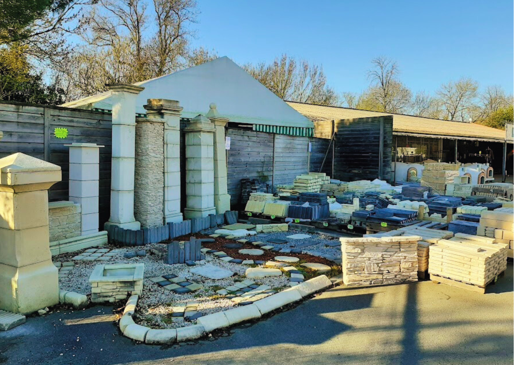 Showroom extérieur Marais Fleuri présentant des piliers en pierre, des bordures et différents modèles de pavés en situation.