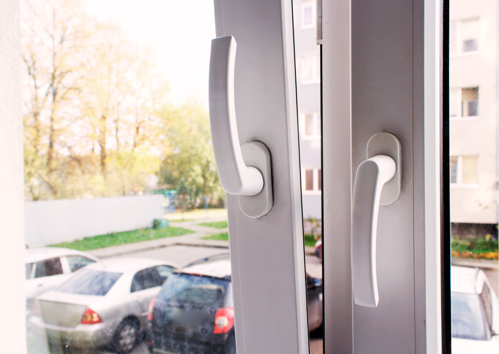 Gros plan sur les poignées ergonomiques blanches d'une fenêtre double vitrage en PVC, disponible chez Marais Fleuri.