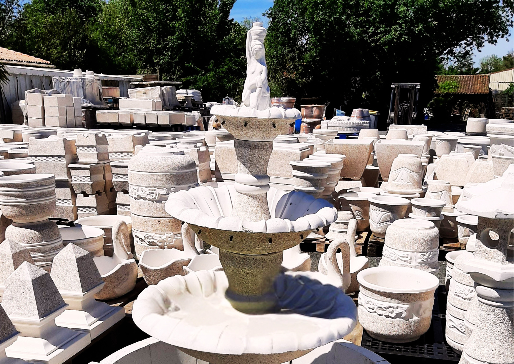 Fontaine centrale de jardin en pierre reconstituée exposée sur le parc de stockage du magasin Marais Fleuri