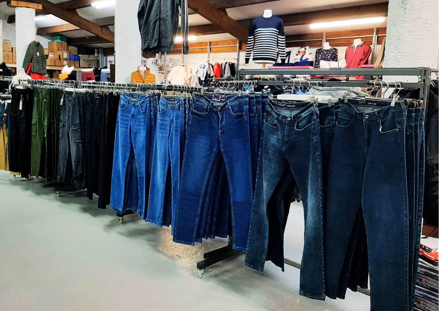 Grand choix de jeans denim (différentes coupes et coloris) présentés sur portants chez Marais Fleuri.