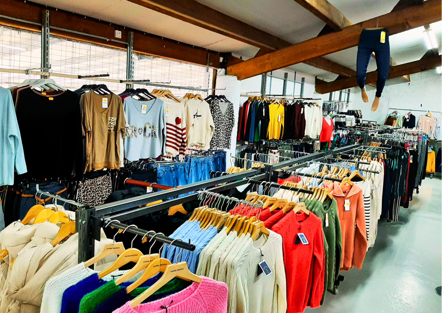 Large choix de vêtements de marque (pulls colorés, sweats, jeans) dans le rayon prêt-à-porter du magasin Marais Fleuri.