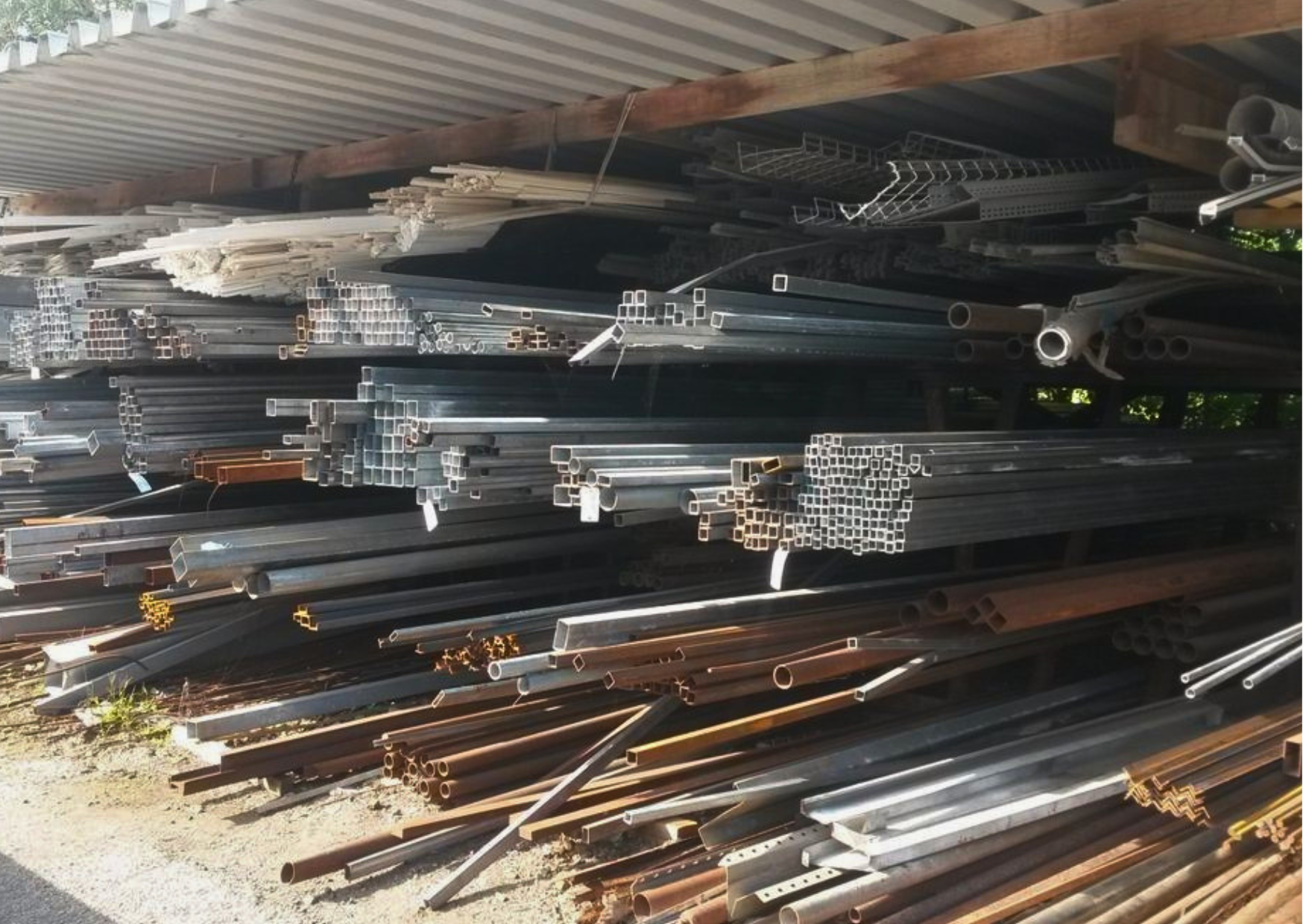 Stock de barres, tubes carrés en acier et profilés métalliques sous abri chez Marais Fleuri.