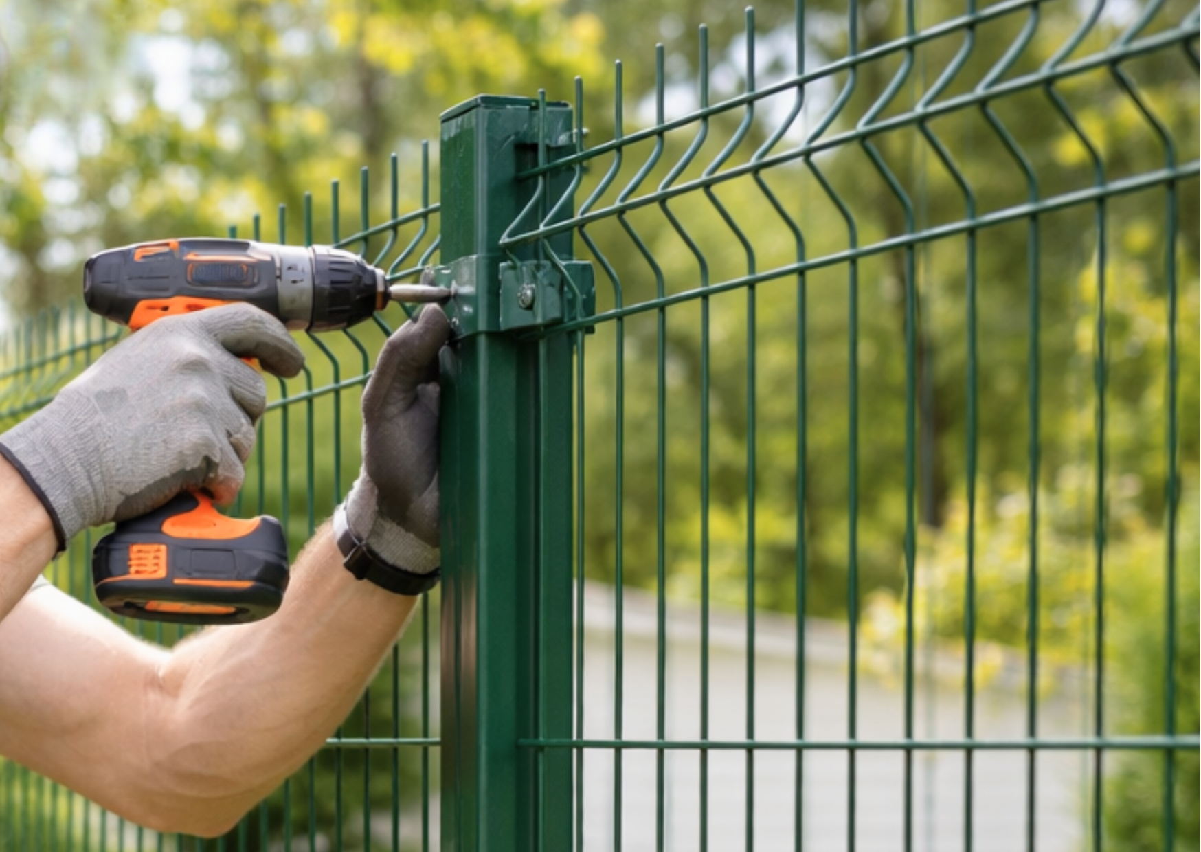 Fixation d'un panneau rigide vert sur poteau avec perceuse-visseuse lors de l'installation d'une clôture de jardin chez Marais Fleuri.