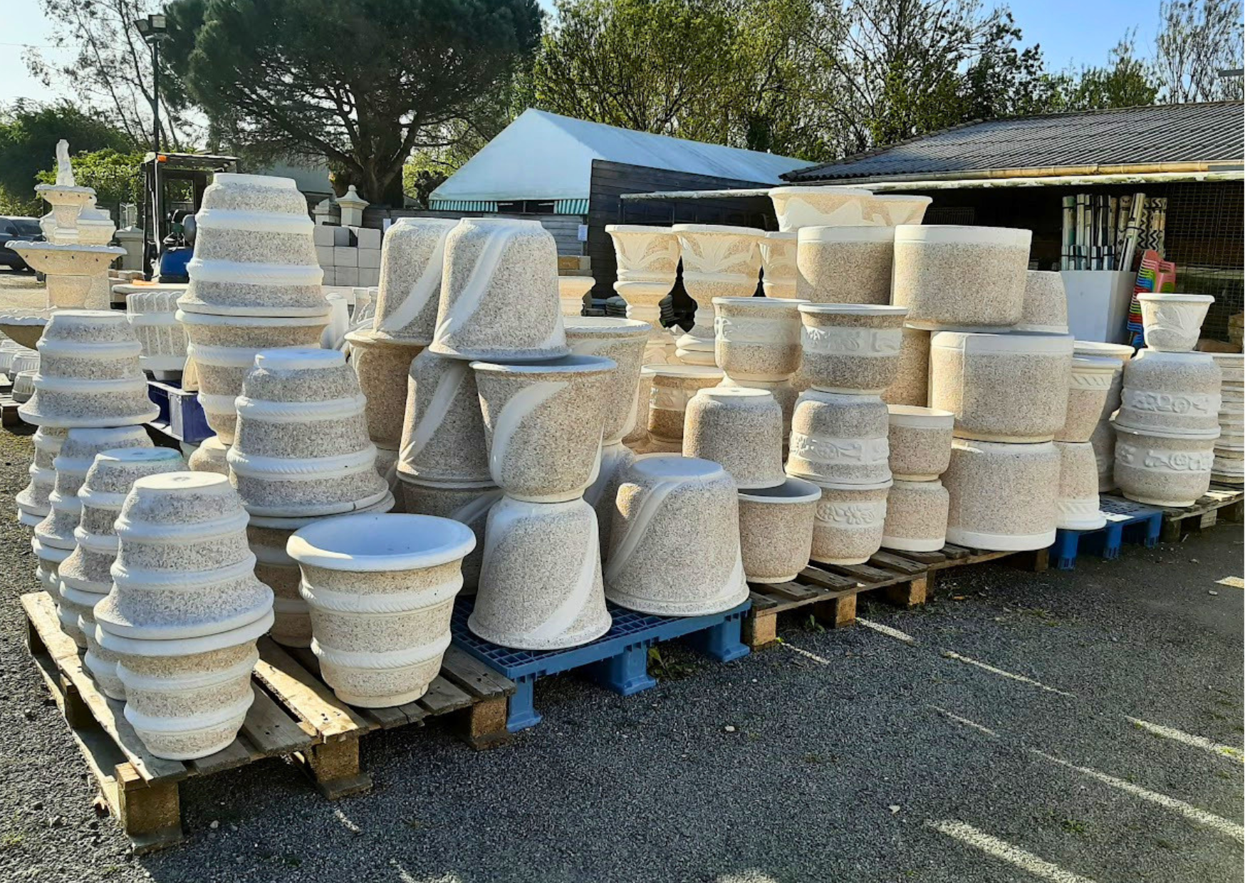Exposition de pots, vases et bacs à fleurs en pierre reconstituée ton pierre et motifs gravés en stock chez Marais Fleuri à Marans.