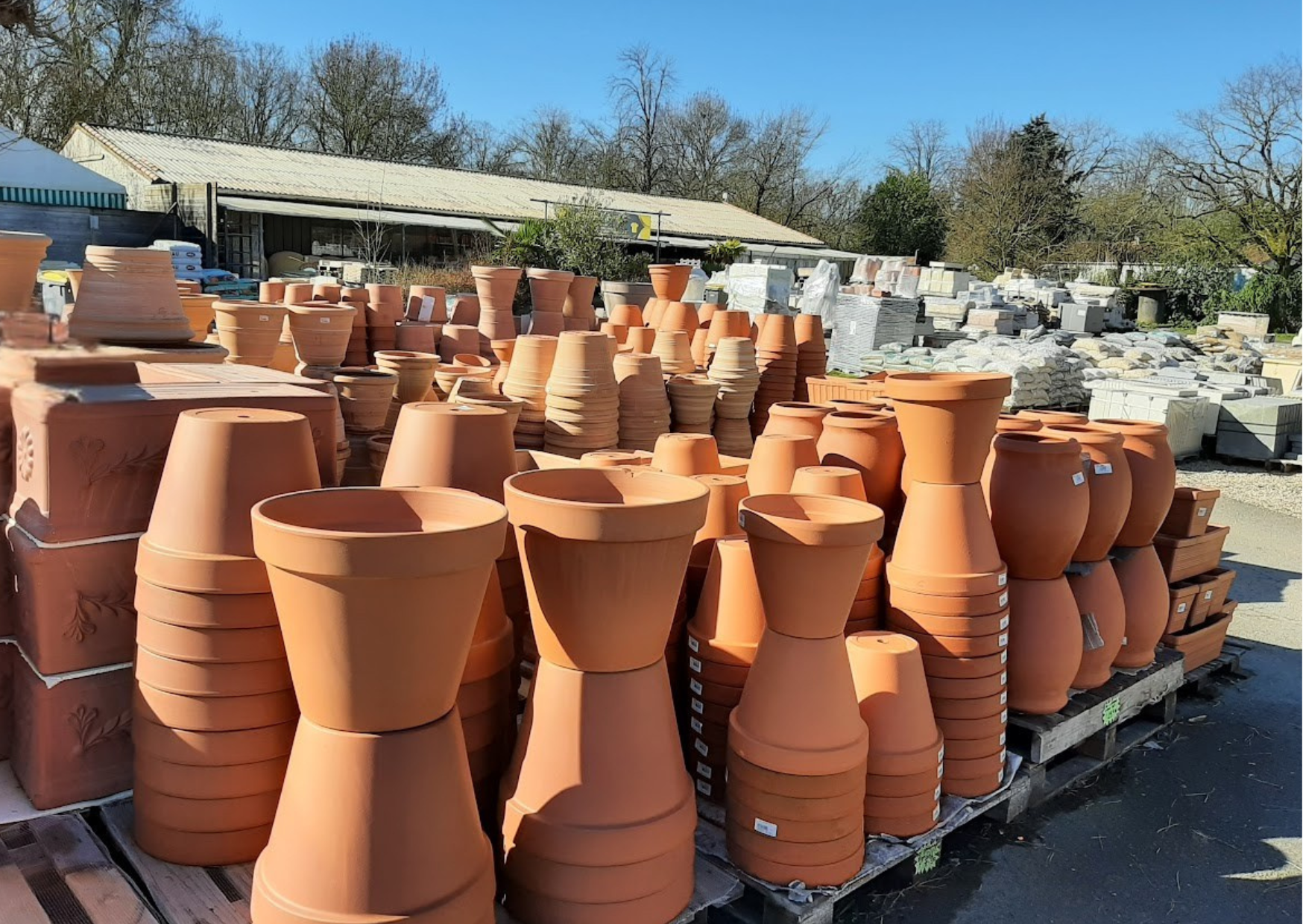 Exposition de pots, vases et jardinières en terre cuite naturelle de différentes tailles en stock chez Marais Fleuri à Marans.