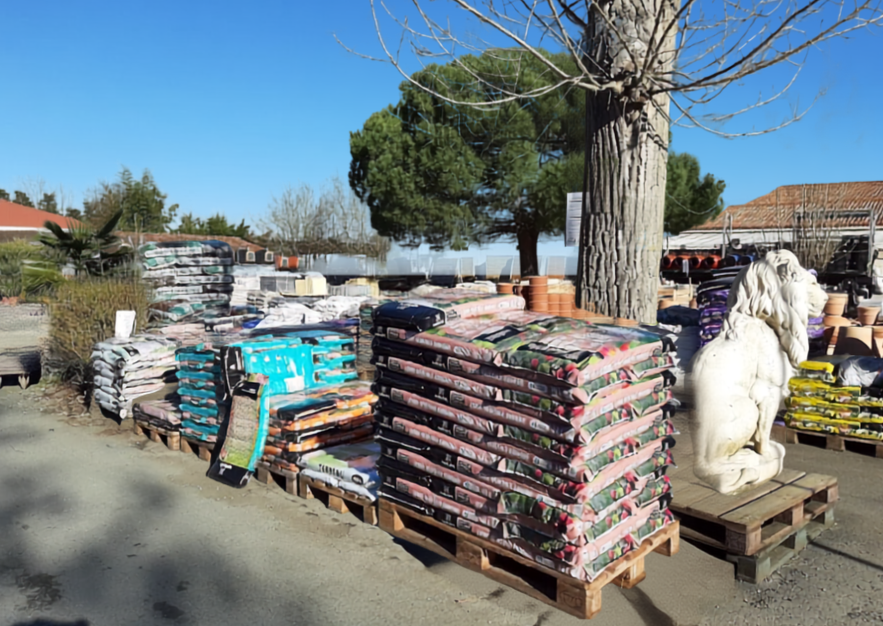 Palettes de sacs de terreau, paillage et amendant pour le jardin sur le parc extérieur chez Marais Fleuri.