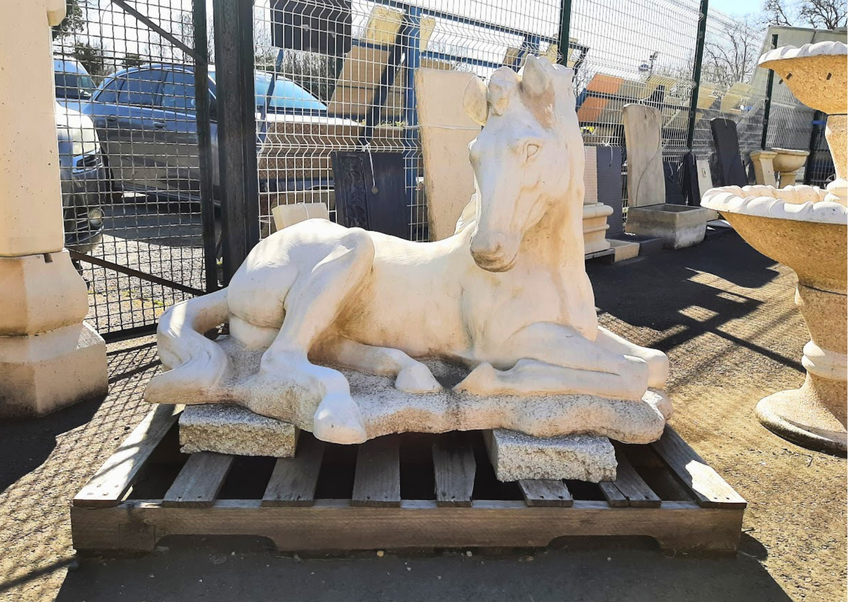 Statue de cheval couché en pierre reconstituée pour décoration de jardin et extérieur en stock chez Marais Fleuri.