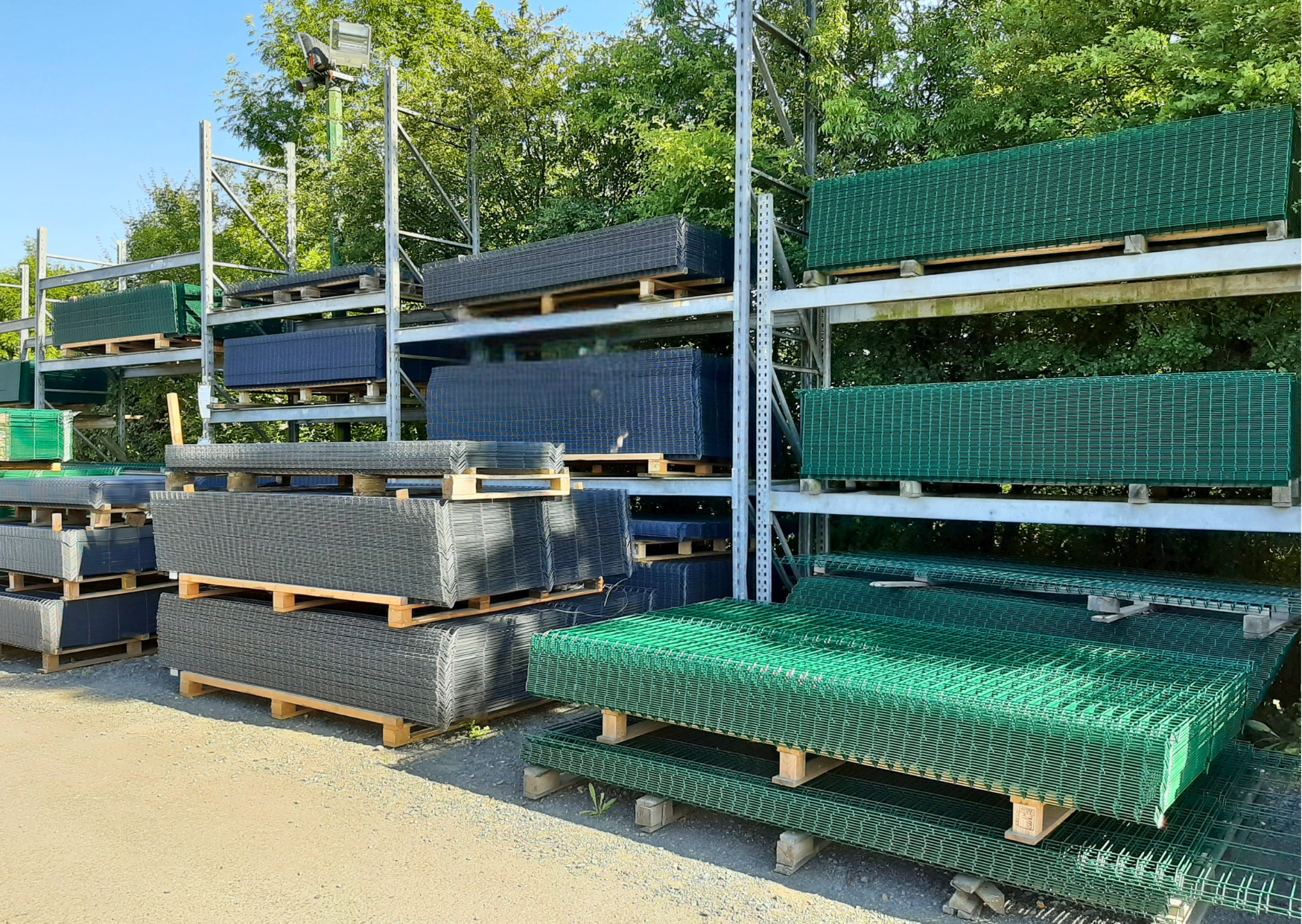 Racks de stockage extérieurs remplis de palettes de panneaux rigides verts et gris anthracite chez Marais Fleuri à Marans (17) et Mareuil-sur-Lay (85).